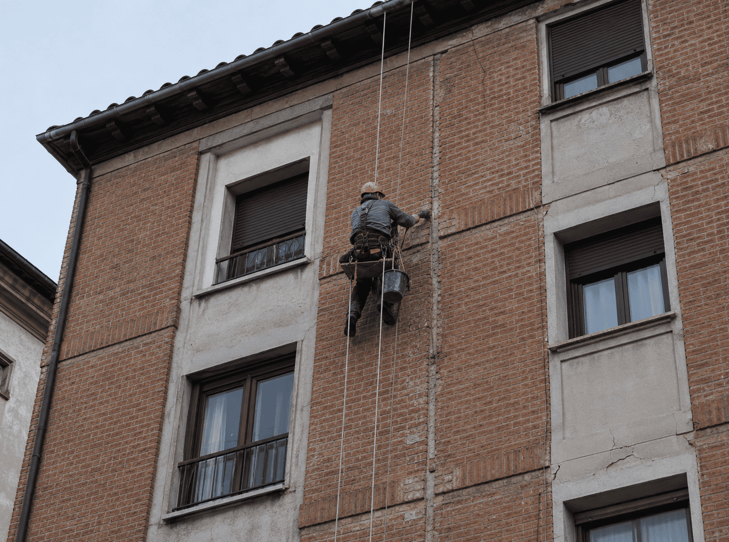 Operario reparando una fachada en Ávila mediante trabajos verticales en altura, sin andamio